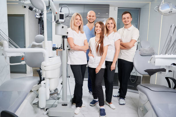 Team of professional dentists and assistants looking at camera and smiling while posing in modern dental office. Dream team. Dentistry and medicine concept.